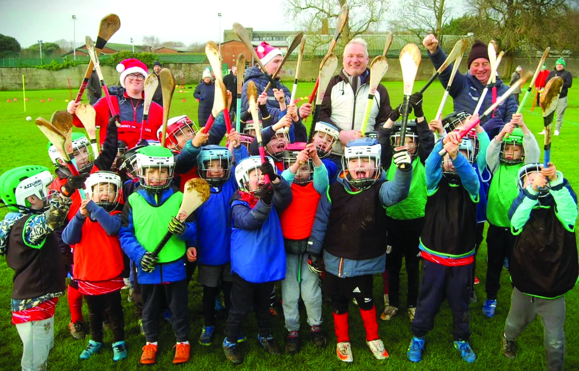 Nursery hurling group and coaches holding hurls aloft, Christmas session